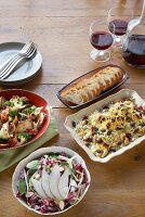 Three Assorted Salad; Sliced Bread; Carafe and Glasses of Red Wine