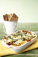 Warm Spinach Dip in Baking Dish with Crackers in a Pail