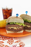 Cheese Stuffed Hamburger; Halved on a Plate with Corn on the Cob; Glass of Coke