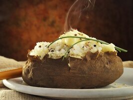 Dampfender Baked Potato mit Butter und Schnittlauch
