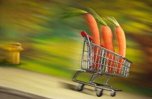 Three carrots in a shopping cart rolling down the street