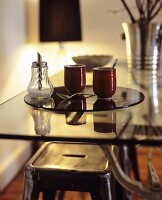 Two mugs and a sugar shaker on a glass table