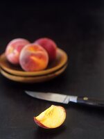 Pfirsichspalte und ganze Pfirische mit Messer
