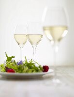 Mixed leaf salad with edible flowers and glasses of white wine