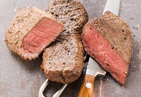Two beef steaks, with knife and meat fork