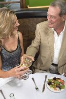 Man & women clinking glasses of wine in restaurant