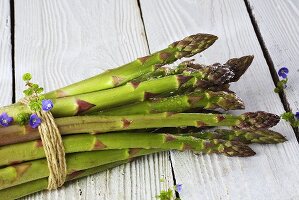 A bundle of green asparagus on white wood