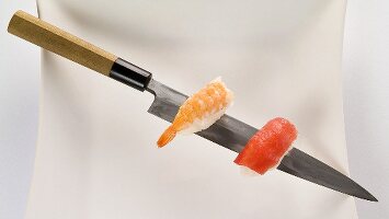 Prawn and salmon nigiri on a sushi knife