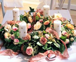 Christmas wreath with flowers and candles with stars on table