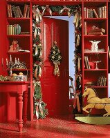 Rotgestrichene Tür, geschmückt mit Girlande, Schaukelpferd , Engel