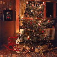 Weihnachtsbaum mit dicken Kerzen und kleinen Holzfiguren