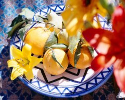 Close-up of oranges, pears and exotic yellow flower in bowl