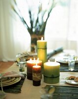 Brennende Kerzen, teilweise mit mehreren Dochten,  als Tischdekoration