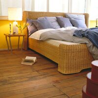 Bett aus Rattangeflecht mit Bett- Wäsche in verschiedenen Blautönen