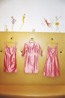 Drei rosa Satinkleider hängen am Kleiderbügel (Cynthia Rowley-Design)