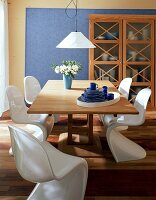 Eßzimmer: fünf weiße Panton-Stühle, heller Tisch,Vitrinen-Schrank
