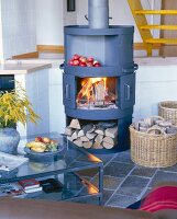 Apple on wood burning stove, basket of wood and table in living room