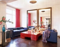 Wohnraum mit großem rotem Tisch und zwei raumhohe Spiegel