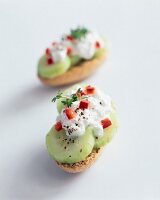 Crackers with topping of cucumber and cream cheese on white background