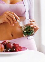 Woman wearing lingerie holding glass with mint and spoon