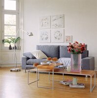 Reduziert eingerichteter Raum mit grauem Sofa und Beistelltischen