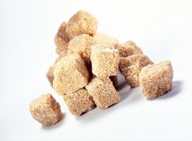Close-up of brown raw sugar cubes on white background