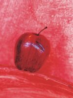 roter Apfel vor rotem Hintergrund 