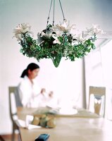 Close-up of chandelier frame decorated white lilies and twisted ivy