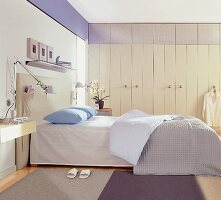 Schlafzimmer in zarten Farben, weiße Schrankwand, Ablagemöglichkeiten