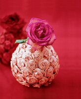 Mit Papierrosen beklebte Vase aus einer Styroporkugel mit einer Rose