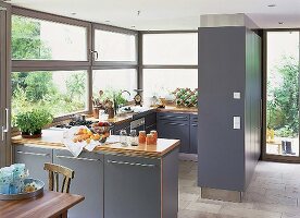 Offene Küche mit viel Fensterfläche, blau-graue Schränke