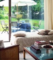 Blick aus dem Wohnzimmer auf die Terrasse mit Tisch + Sonnenschirm