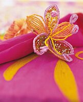 Serviettenring: Bunte Blüte aus Glas perlen um pinkfarbene Stoffserviette