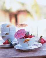 weiße Schale mit Erdbeeren u. buntem Papierschirmchen dekoriert