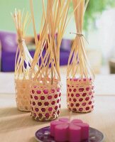 Kleine Bambuskörbchen umhüllen pinkfarbene Kerzen