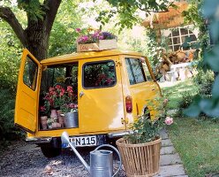 bunte Blumen fürs Beet in Holzbox + Töpfen im Laderaum 1 gelben Autos