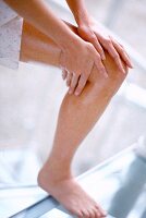 Close-up of woman applying oil on her legs