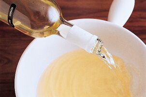 In einen Topf wird für ein Käsefondue Weißwein gegossen. Nr.4