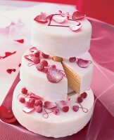 Three-tier wedding cake with raspberries and rose petals