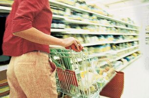 Frau schiebt Einkaufswagen durch Supermarkt, Einkaufen