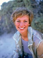 Portrait of pretty woman with short hair wearing jacket, smiling widely