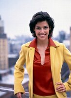 Portrait of young woman with dark hair wearing yellow blazer over red blouse, smiling