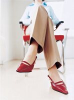 Körpersprach: eine Frau sitzt auf einem Stuhl, Beine übereinander