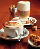 Cup of cappuccino with glass of milk coffee on table