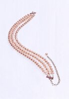 Close-up of champagne-coloured pearl necklace on white background
