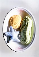 Different shapes of soaps in a bowl on white background, overhead view