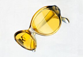 Close-up of stylish yellow sunglasses on white background