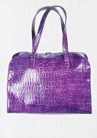 Close-up of purple leather bag on white background