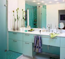 Bathroom with mint green sink and mirrored wall with shower in background