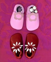 Red and pink leather baby slippers on floral pattern background